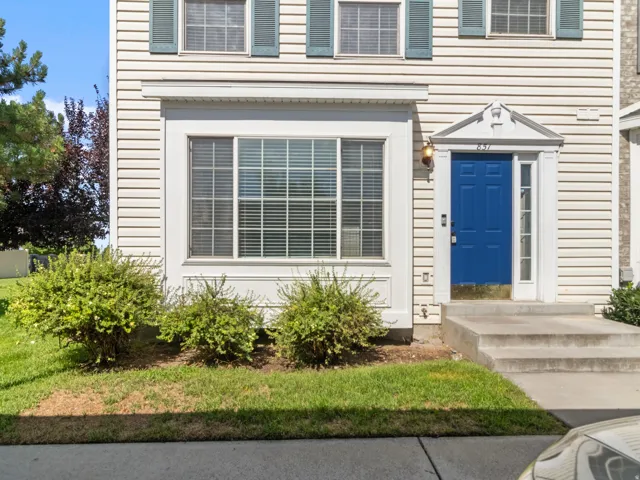 Siding exterior with decorative shutters, prominent front entry with a vibrant blue door, and multiple windows