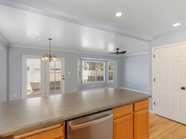 Kitchen island with integrated dishwasher, wood cabinetry, recessed lighting, and bay windows