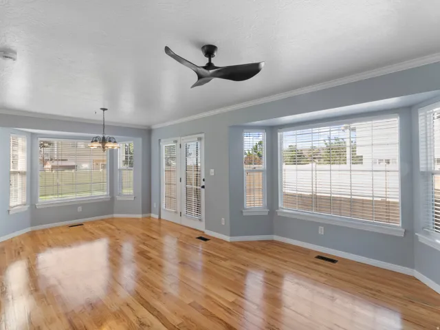 Hardwood flooring, bay windows, ceiling fan, double French doors, and a chandelier lighting fixture