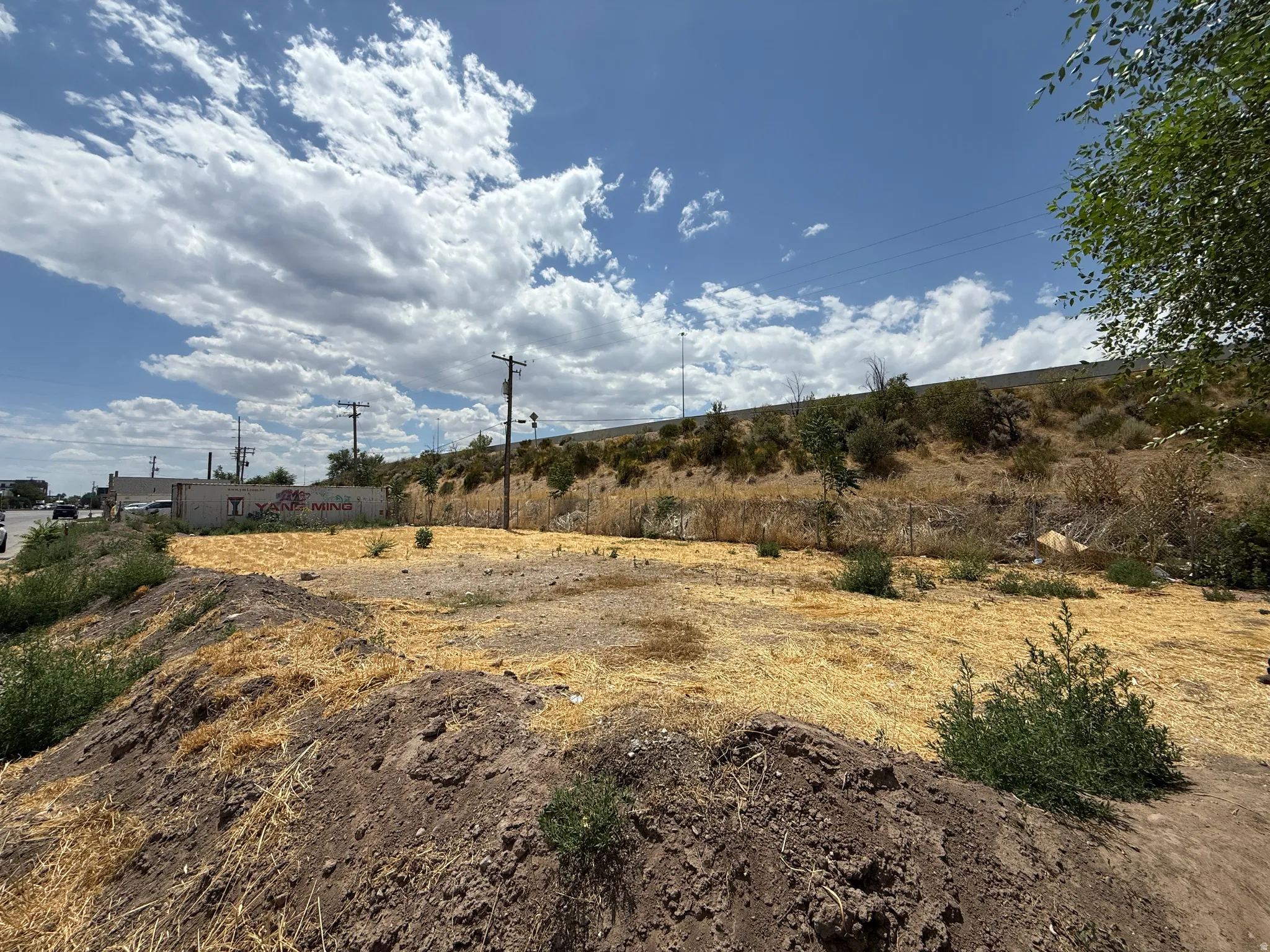 Expansive undeveloped lot featuring a substantial mound of dark earth and scattered dry vegetation