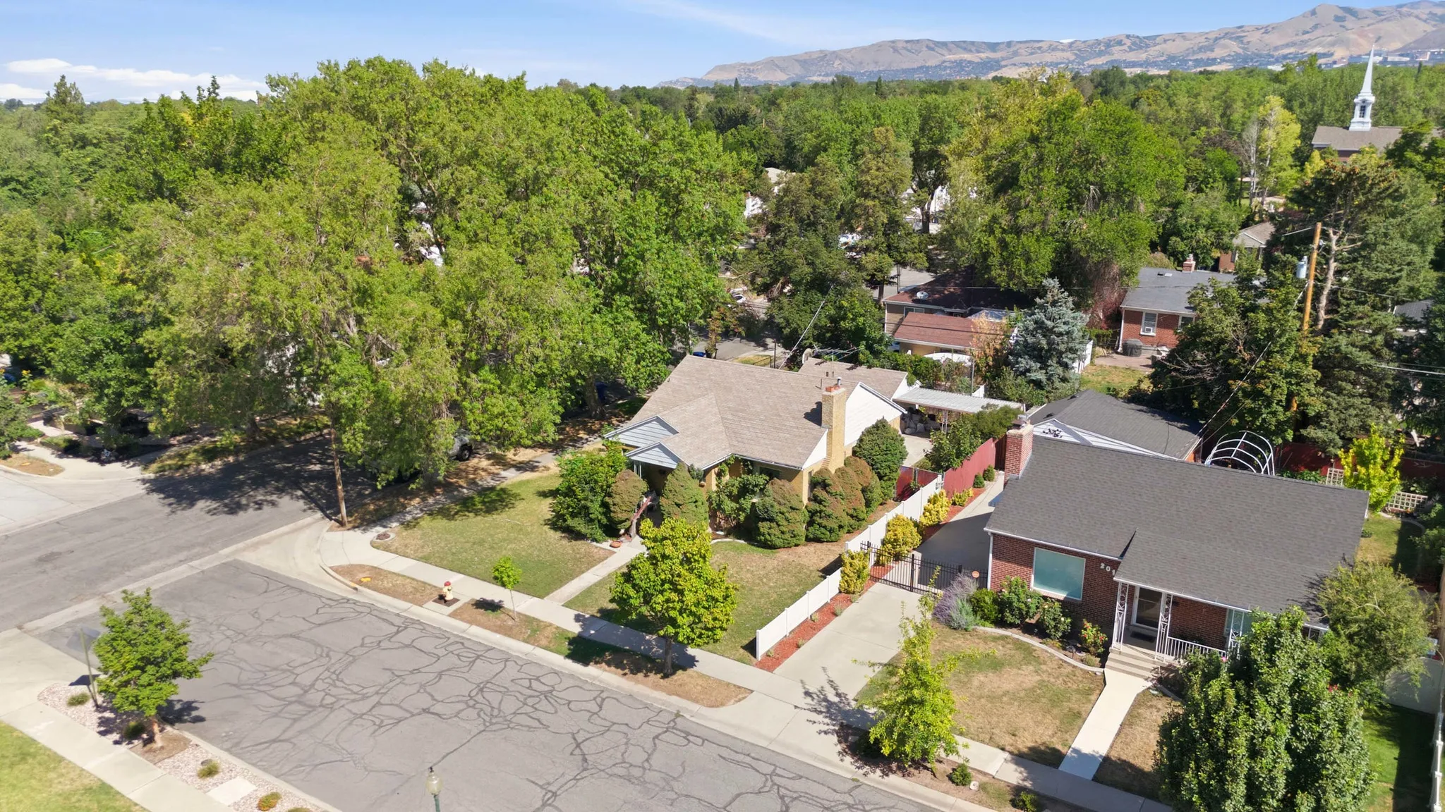 Expansive corner lot featuring a traditional residence with a light-colored roof and brick chimney