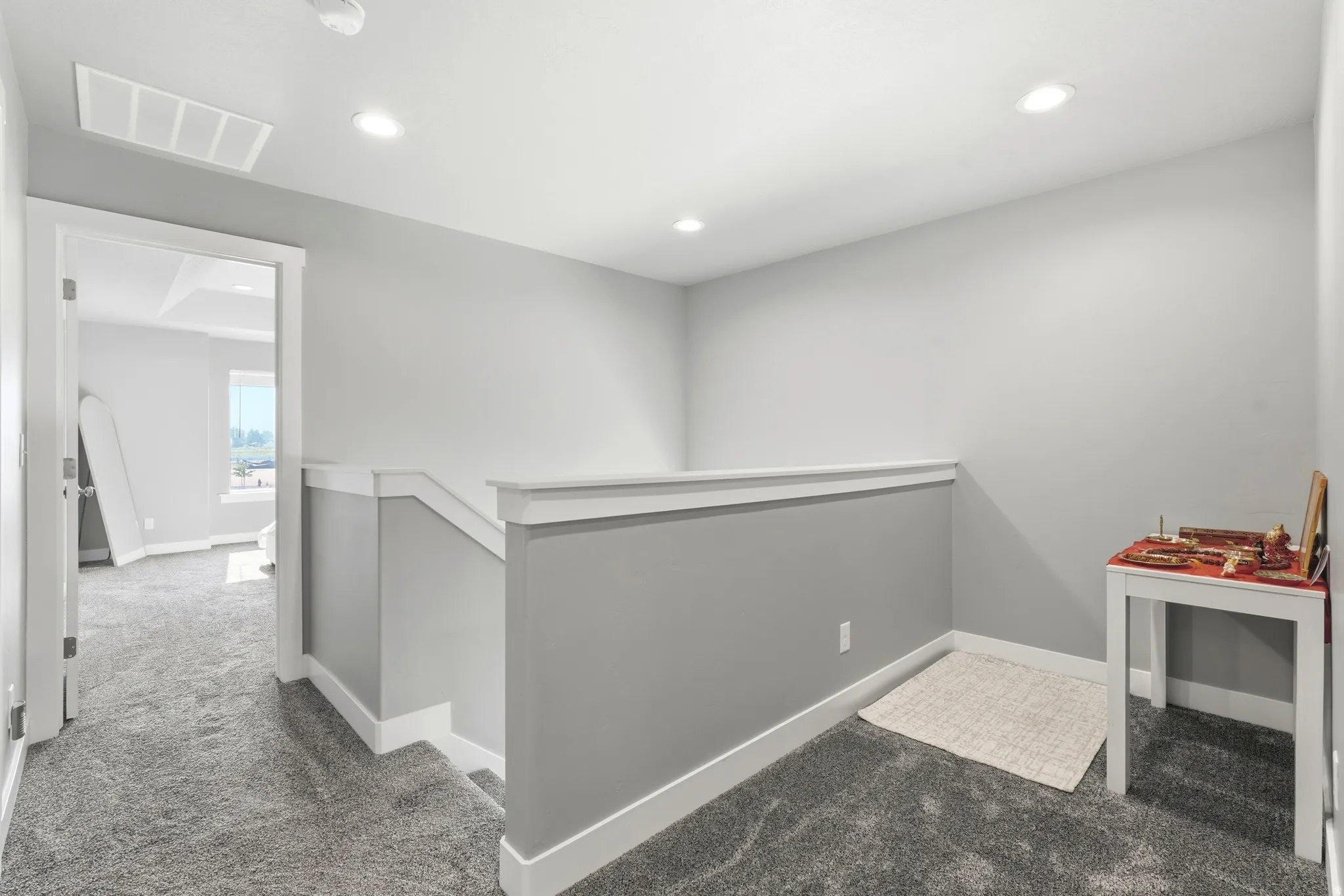 Hallway featuring plush grey carpeting, bright recessed lighting, painted grey walls, and white baseboards