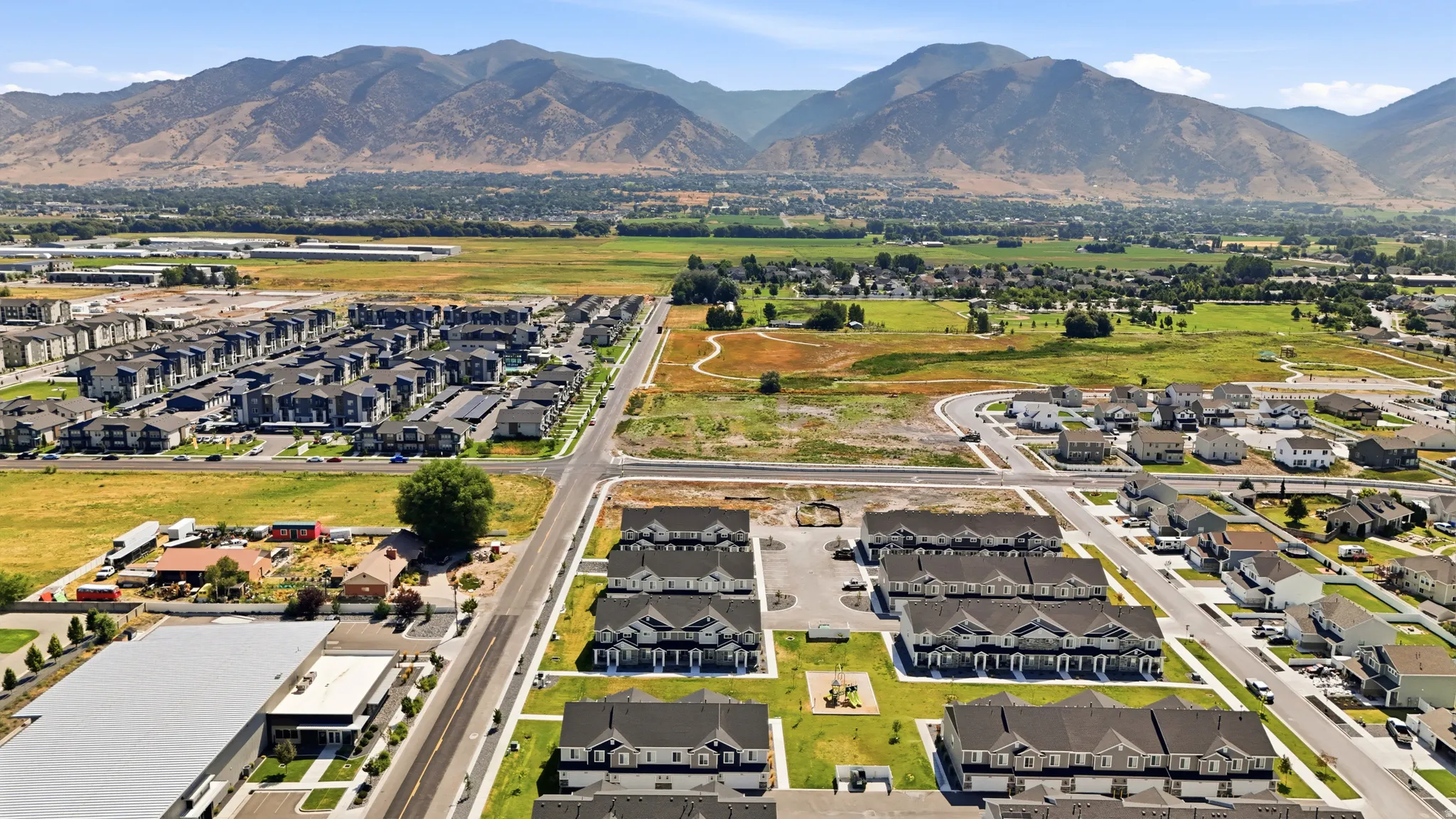 Residential development featuring rows of multi-story townhomes, individual single-family homes, and undeveloped lots