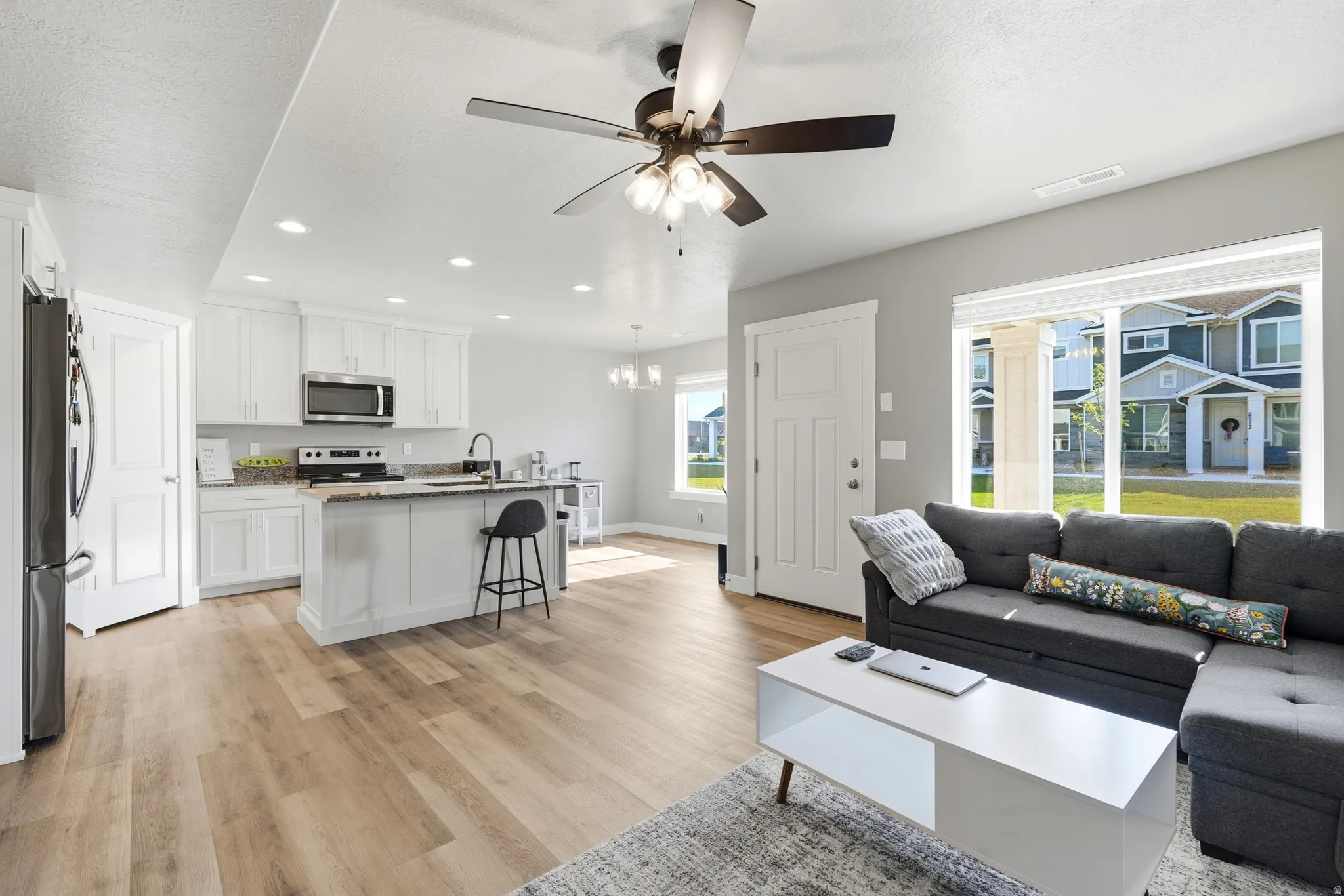 Open-concept living space featuring wood-finish flooring, recessed lighting, and a ceiling fan