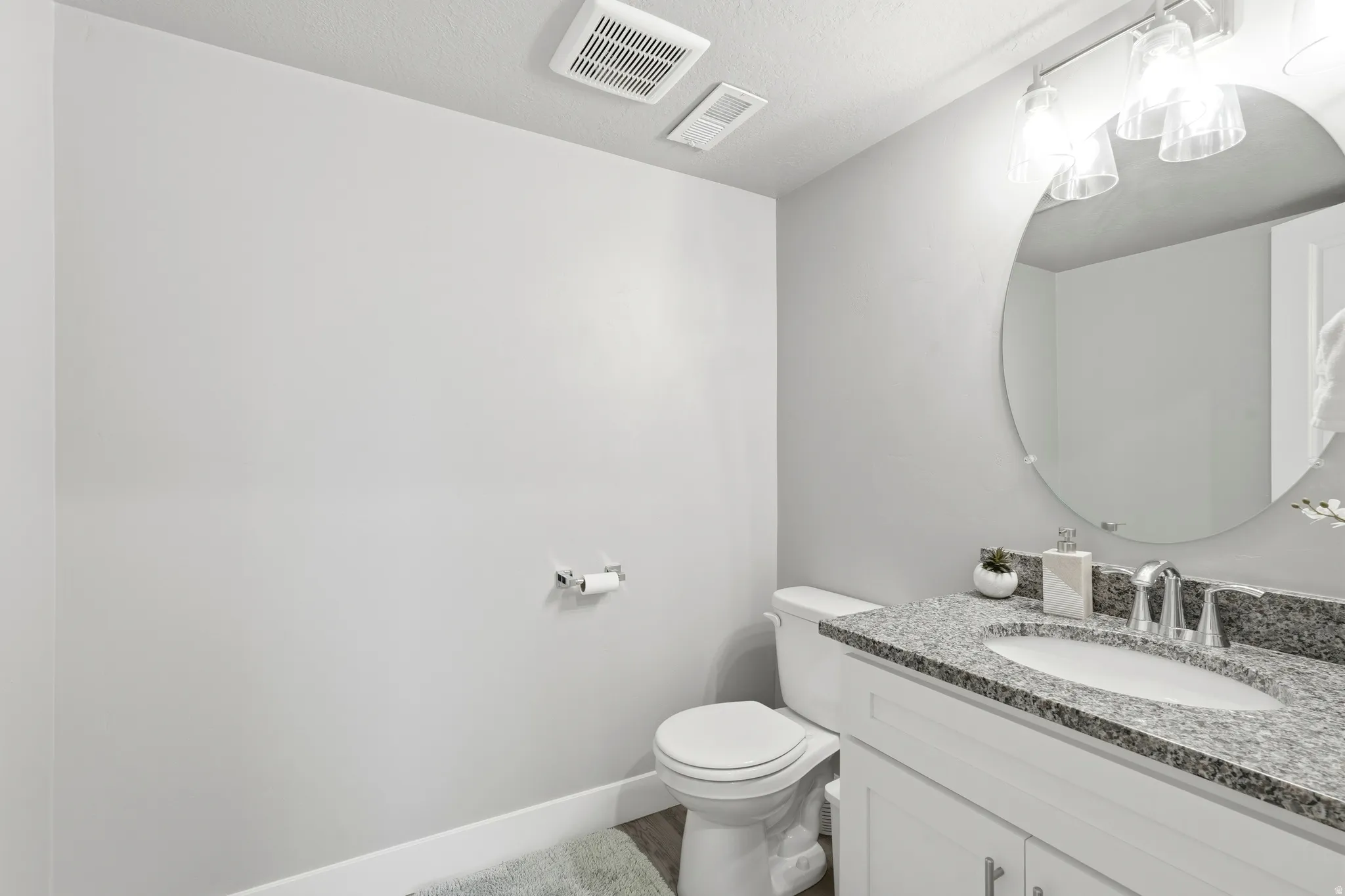 Bathroom vanity featuring a speckled countertop, a white under-mount sink, and a chrome faucet