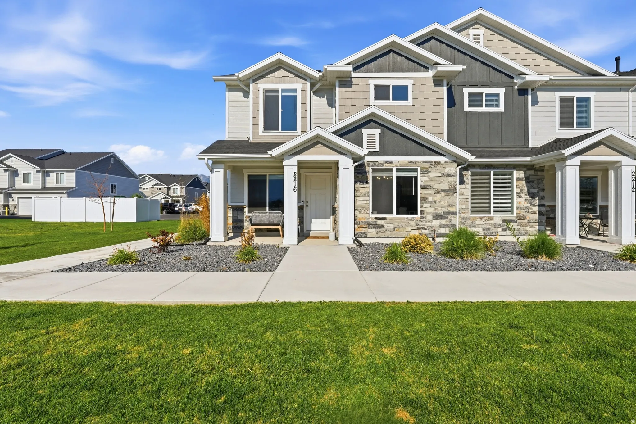 Contemporary townhome exterior featuring multi-toned siding, stone accents, and a covered porch entry