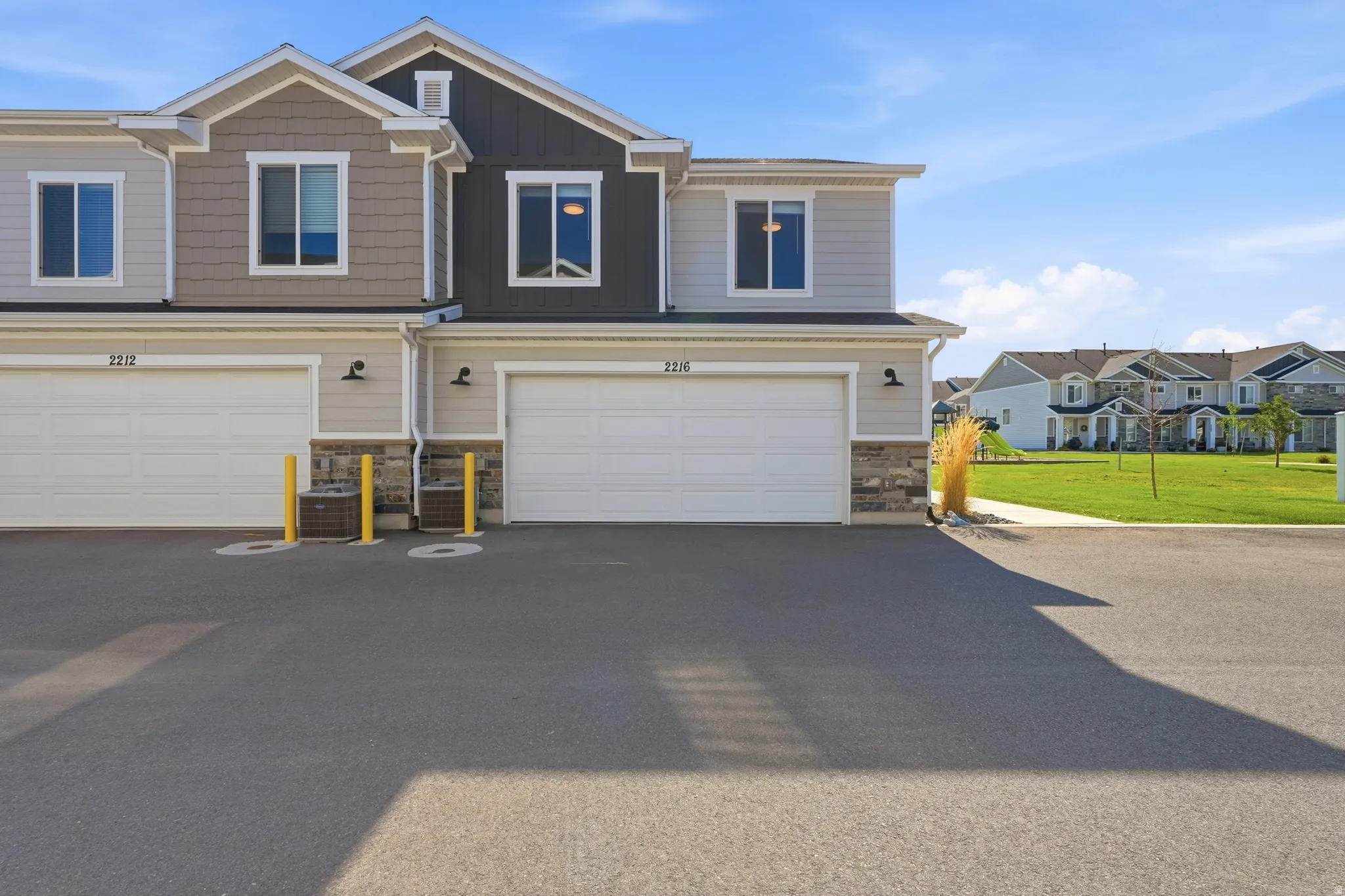 Modern multi-level townhome featuring a two-tone siding exterior, stone accents, and a front-facing garage with overhead door