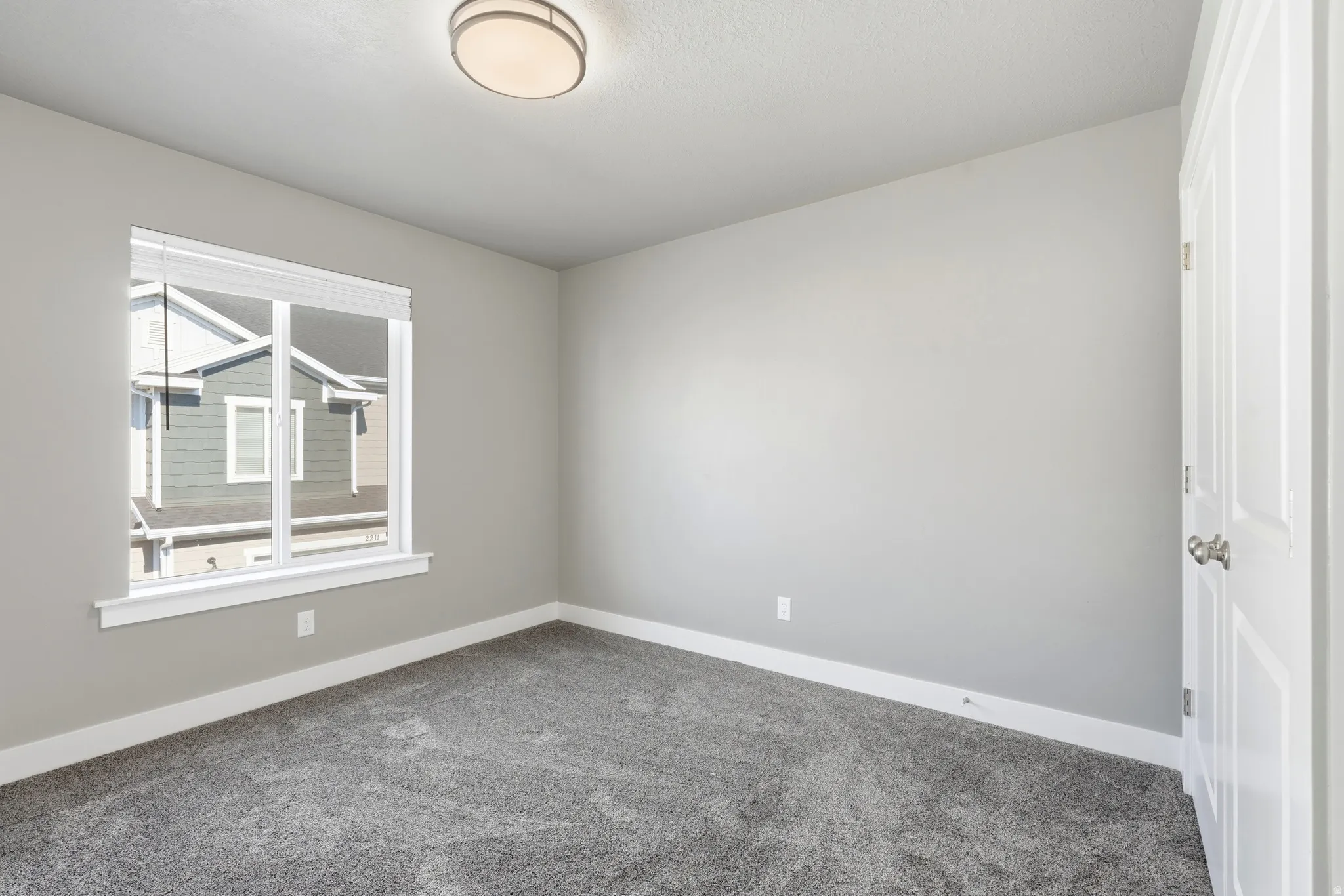 Interior room featuring neutral wall paint, grey patterned carpeting, and white baseboards