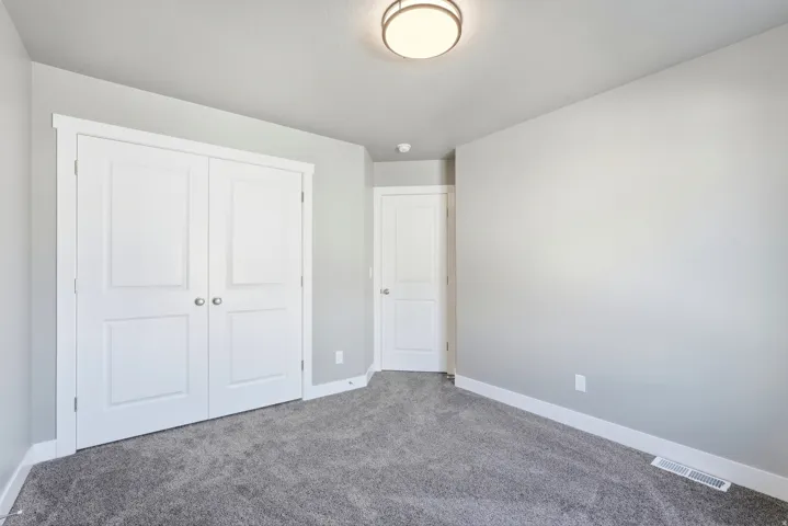 Neutral-toned bedroom featuring plush gray carpeting, white baseboards, and light gray walls