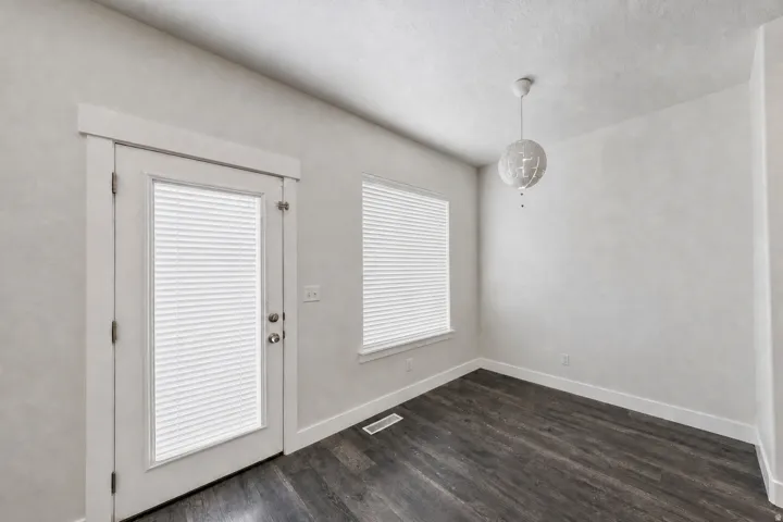 Room featuring dark wood-finish flooring, light grey walls, and white trim