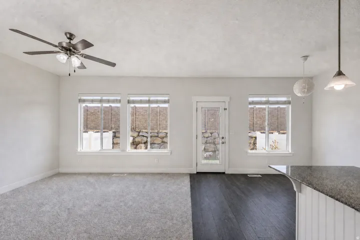 Open-concept living space with dual flooring, featuring dark wood-finish flooring and light gray carpeting