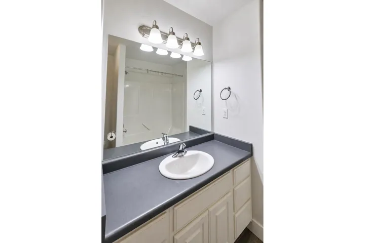 Bathroom vanity with an integrated sink, brushed nickel faucet, and a wall-mounted mirror