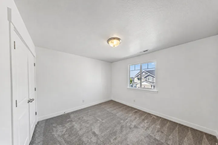 Neutral wall paint, gray carpet flooring, and a multi-pane window with white trim