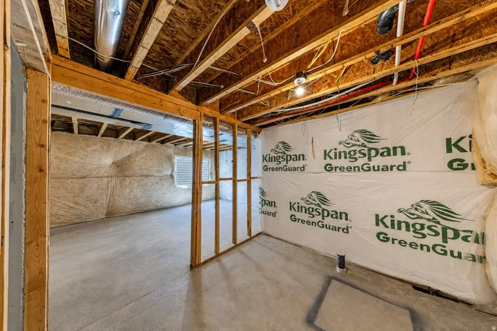 Unfinished basement offering exposed wood joists and subflooring, insulated walls, concrete flooring, and visible ductwork