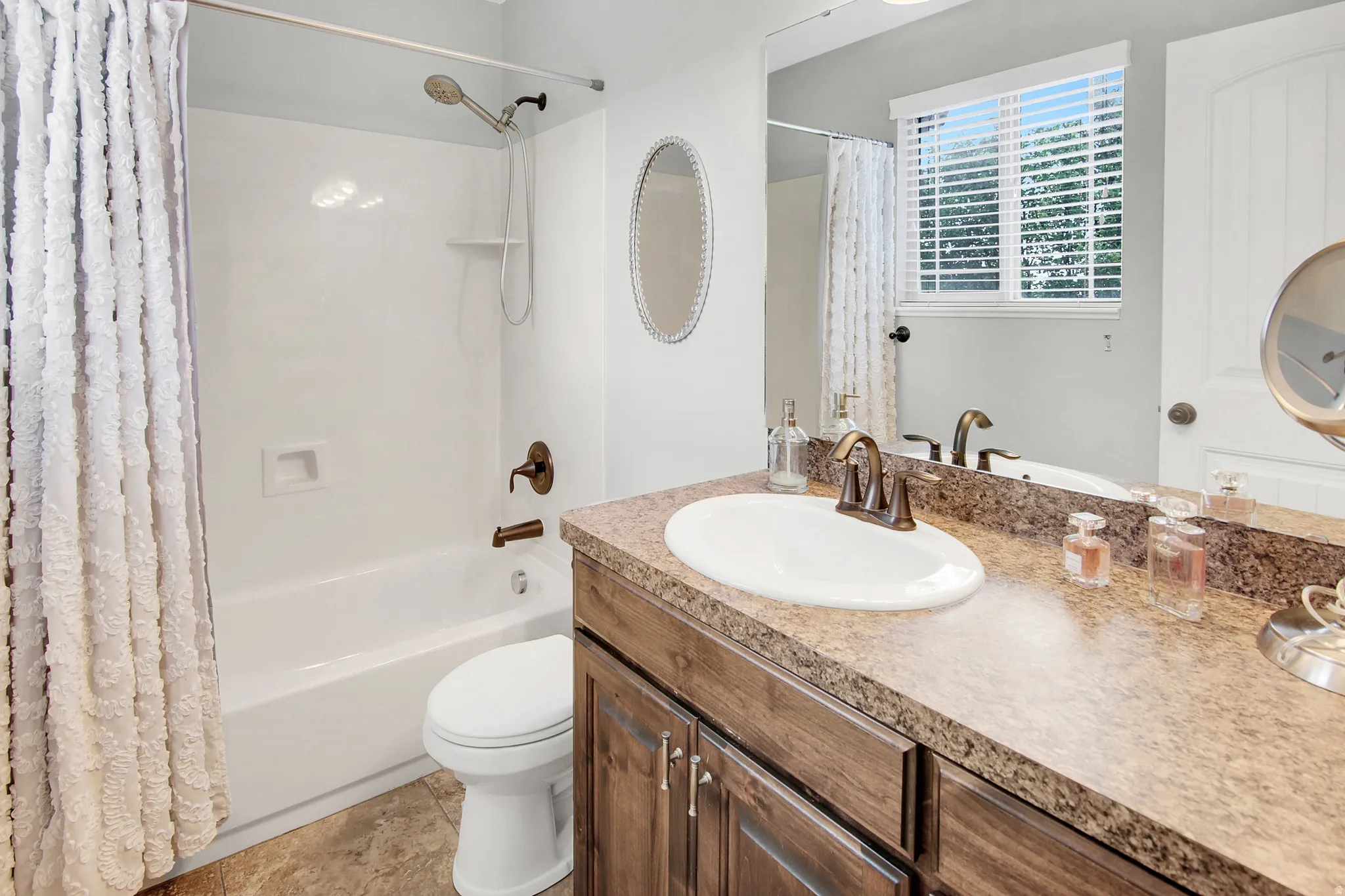Bathroom featuring a wood-finish vanity with an oval sink, solid surface countertop, and bronze-finish fixtures