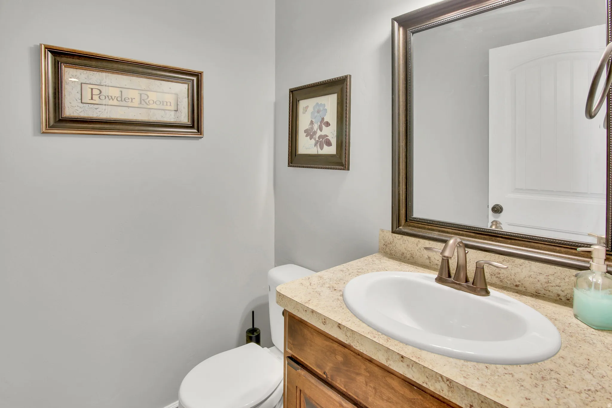 Vanity featuring an oval sink, bronze-tone faucet, and a stone-finish countertop
