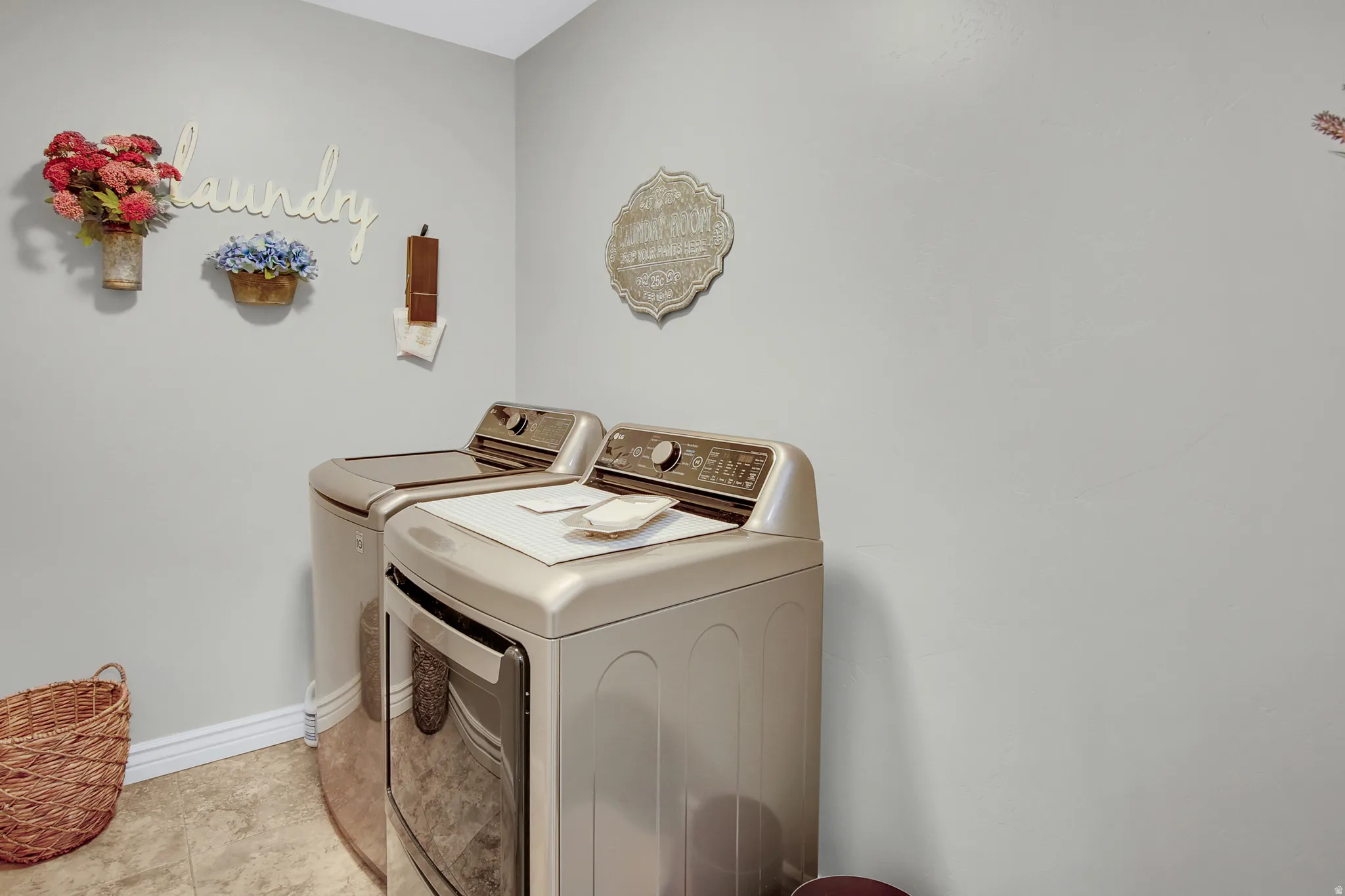 Dedicated laundry room featuring light gray walls, light-colored flooring, and white baseboards