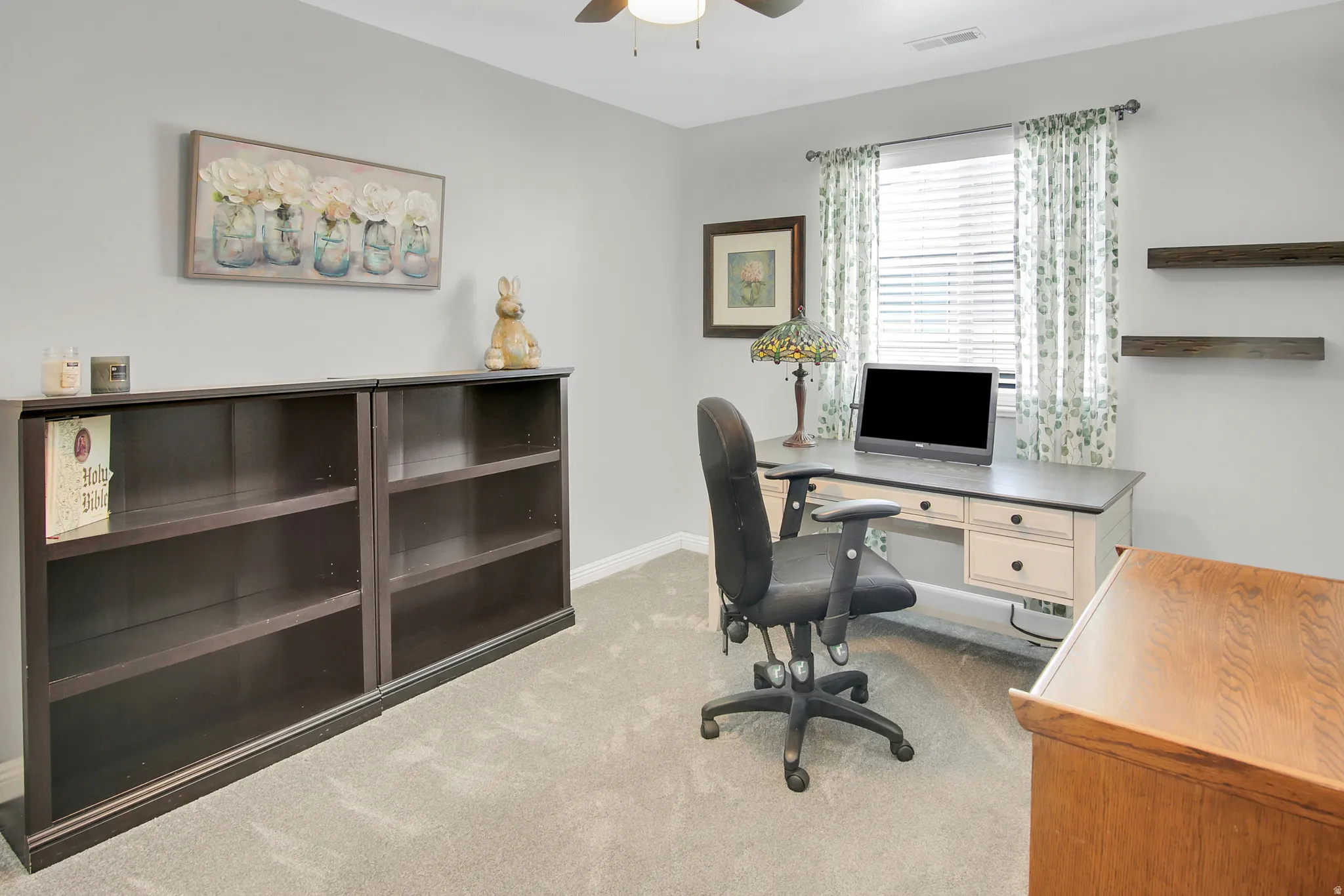 Carpeted room with a ceiling fan, featuring a window with blinds, and built-in shelving