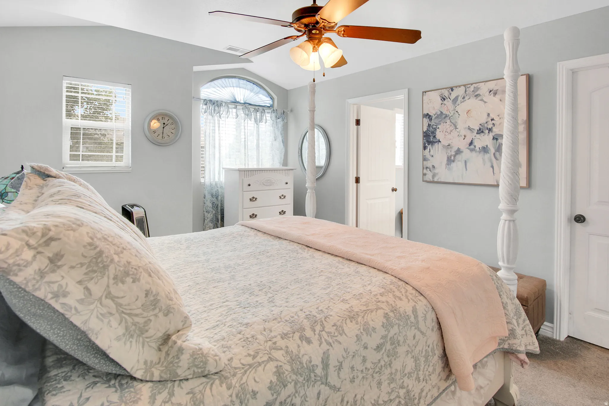 Vaulted ceiling featuring a ceiling fan, light-toned walls, and a window with an arched transom