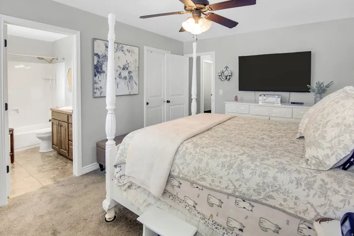 Carpeted room featuring a ceiling fan, a built-in closet with white doors, and light gray walls