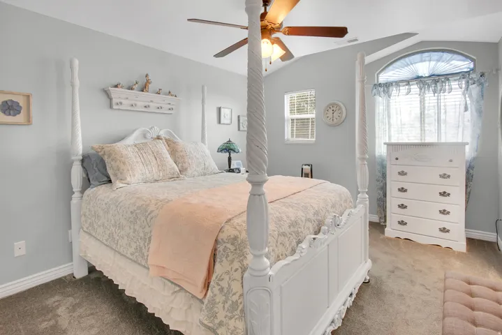 Carpeted room featuring a vaulted ceiling with a ceiling fan