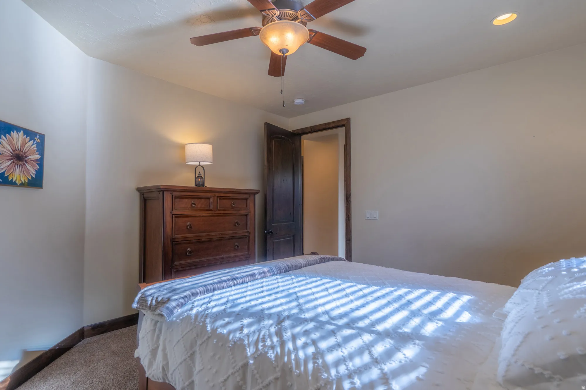 Carpeted room featuring a ceiling fan with integrated lighting, recessed ceiling lighting, and a dark wood-finish door frame