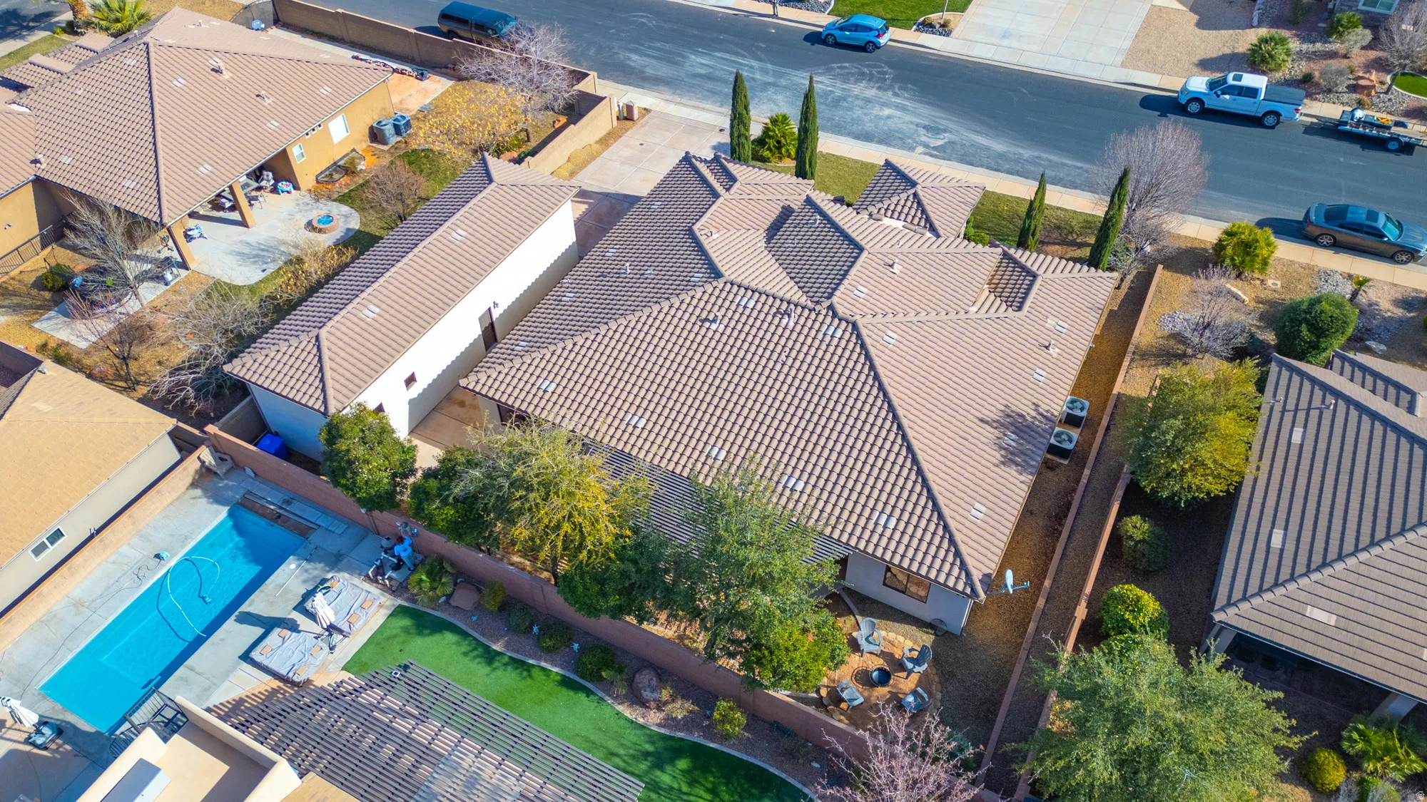 Expansive property featuring a multi-gabled tiled roof, mature landscaping, and a long driveway