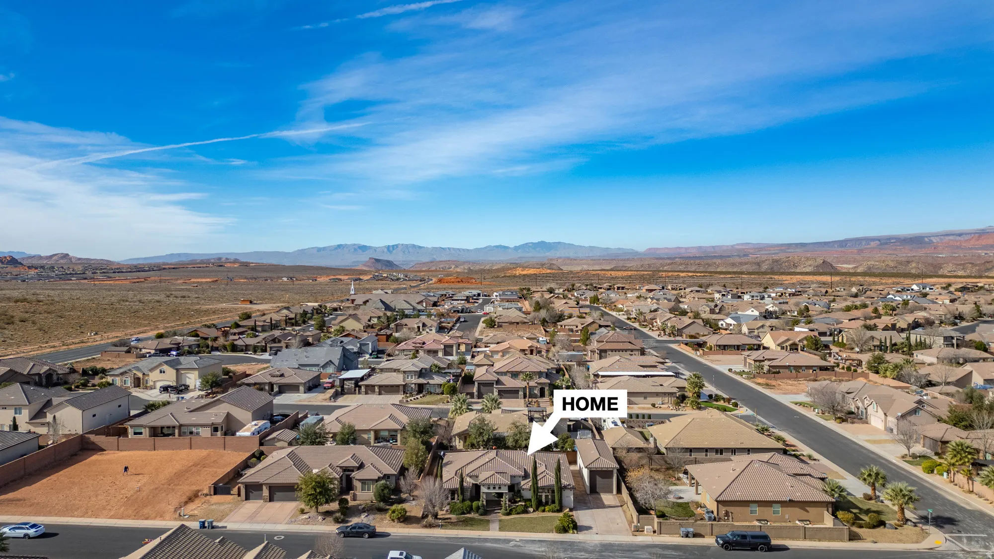 Aerial perspective of a residential neighborhood with surrounding desert landscapes and distant mountains
