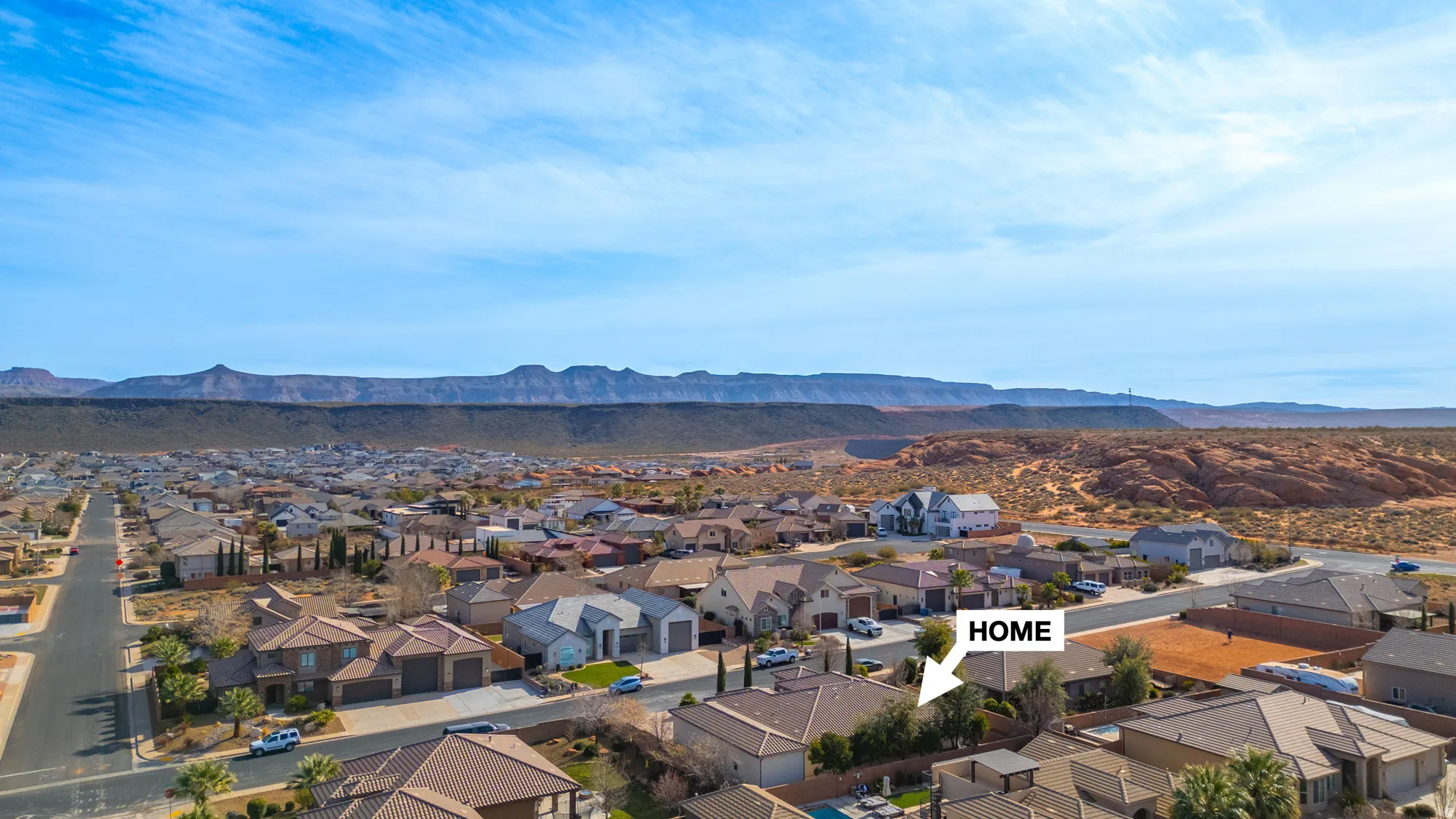 Expansive suburban neighborhood featuring residential homes with diverse architectural styles, a street grid system, and distant desert mountain ranges