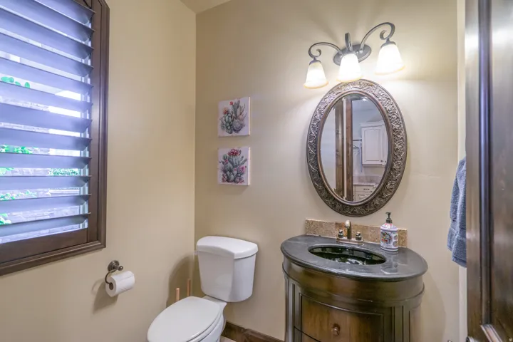 Bathroom featuring a dark wood vanity with a dark countertop and an oval framed mirror