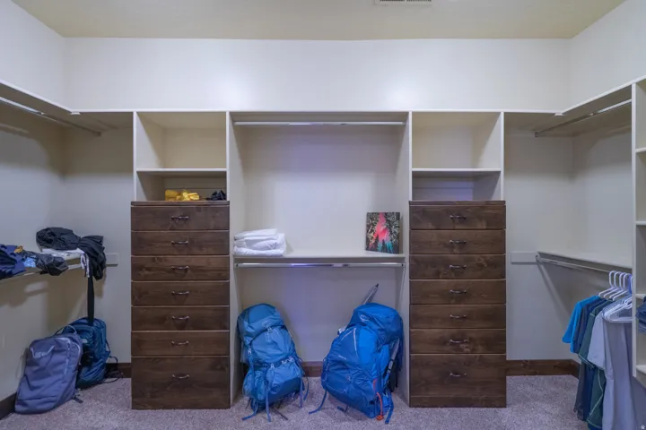Walk-in closet featuring built-in wood-finish drawer units, open shelving, and extensive hanging rods