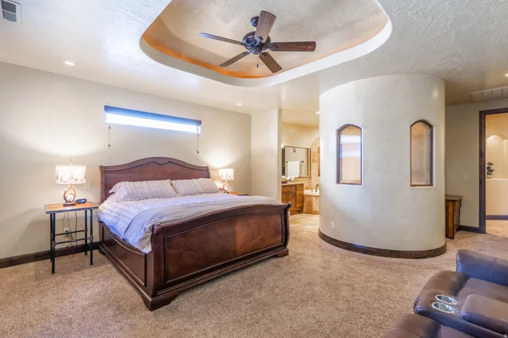 Spacious bedroom featuring a tray ceiling with recessed lighting and ceiling fan