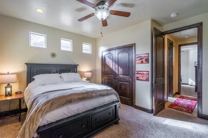 Carpeted bedroom featuring an overhead ceiling fan with lighting, recessed ceiling lights, and three high-set windows