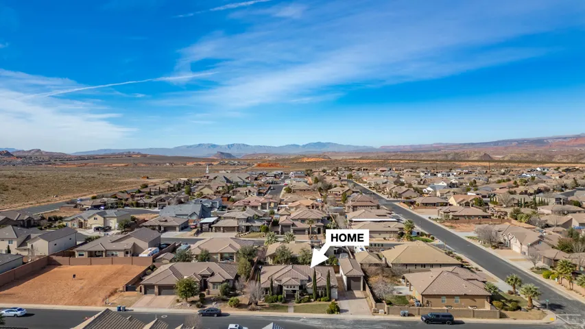 Aerial perspective of a residential neighborhood with surrounding desert landscapes and distant mountains