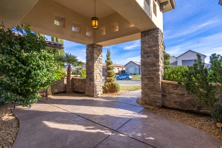 Covered entryway featuring stone-clad pillars, stamped concrete paving, and a decorative overhead light fixture