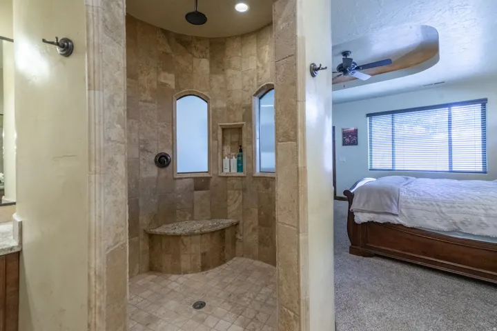 Tiled walk-in shower featuring a built-in bench, recessed shelf, and matte black fixtures