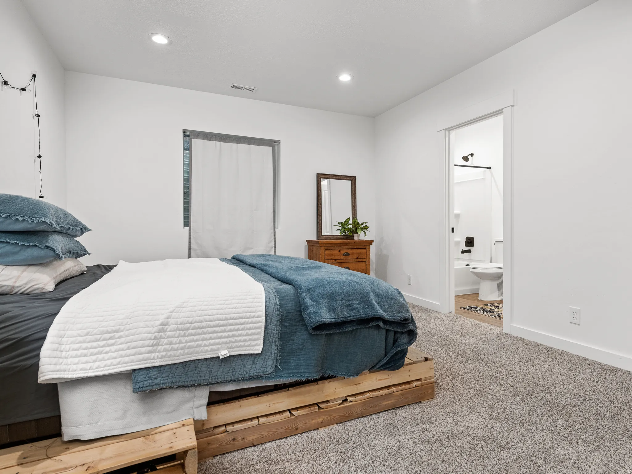 Carpeted sleeping area featuring white walls, recessed lighting, and a window with blinds