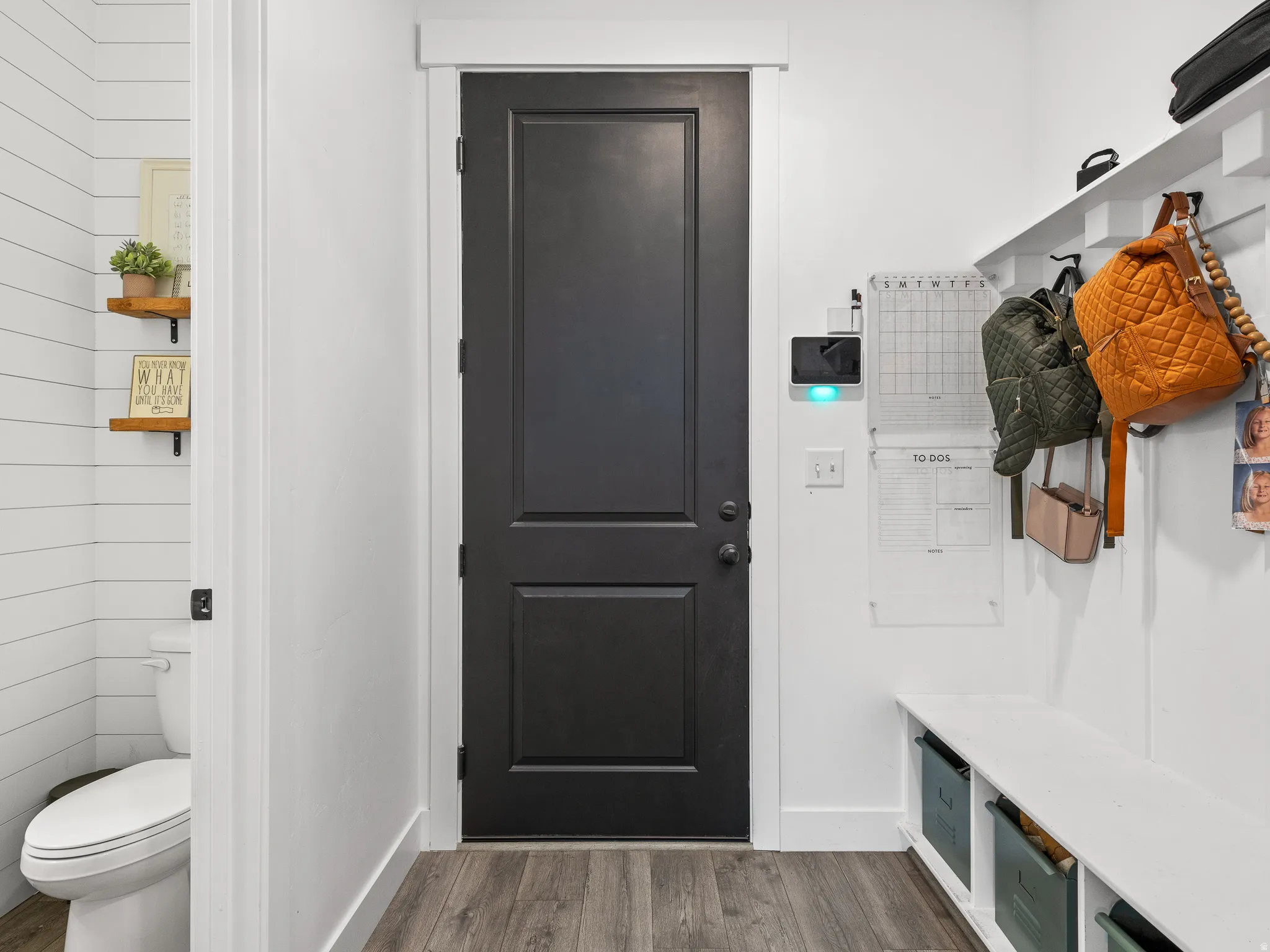 Mudroom entry featuring wood-finish flooring, a built-in storage bench, and a coat rack with shelving