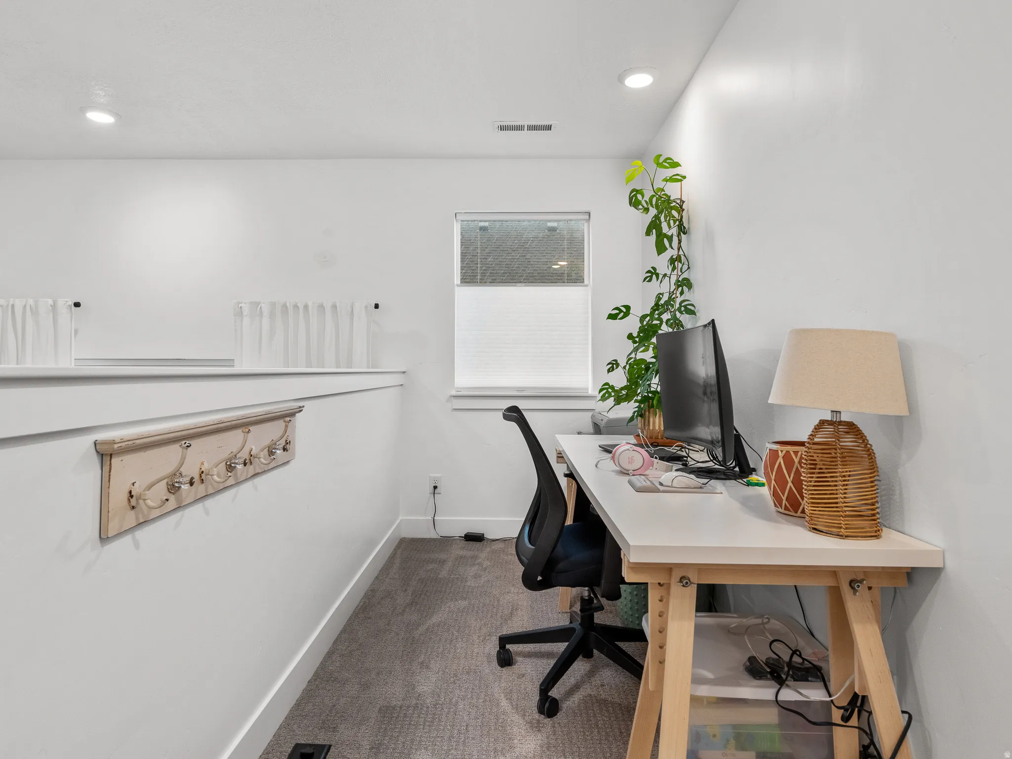 Bright workspace featuring a window with privacy blinds, recessed lighting, and carpet flooring