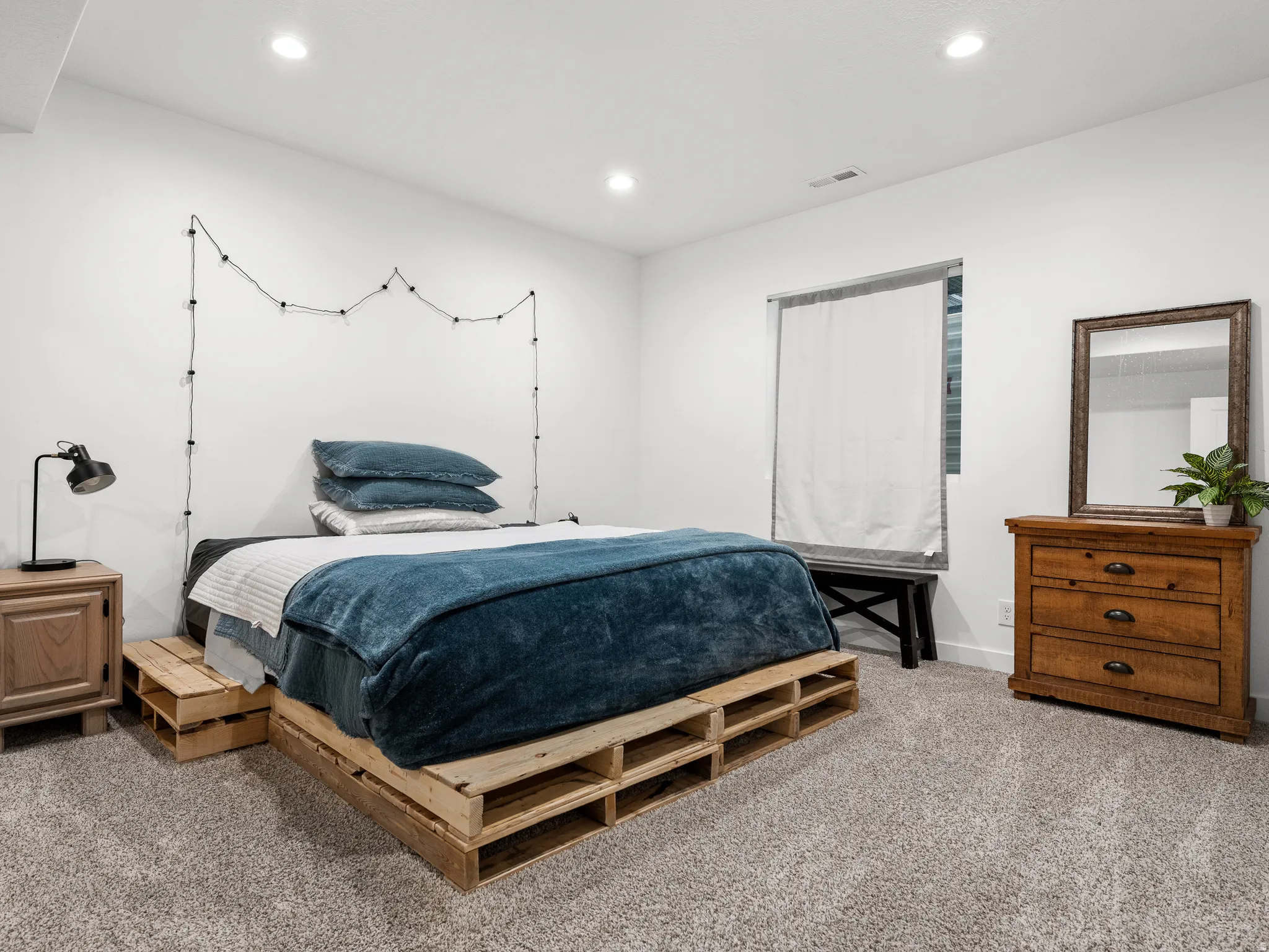 Recessed lighting illuminates this room featuring light-toned carpeting and a window with blinds