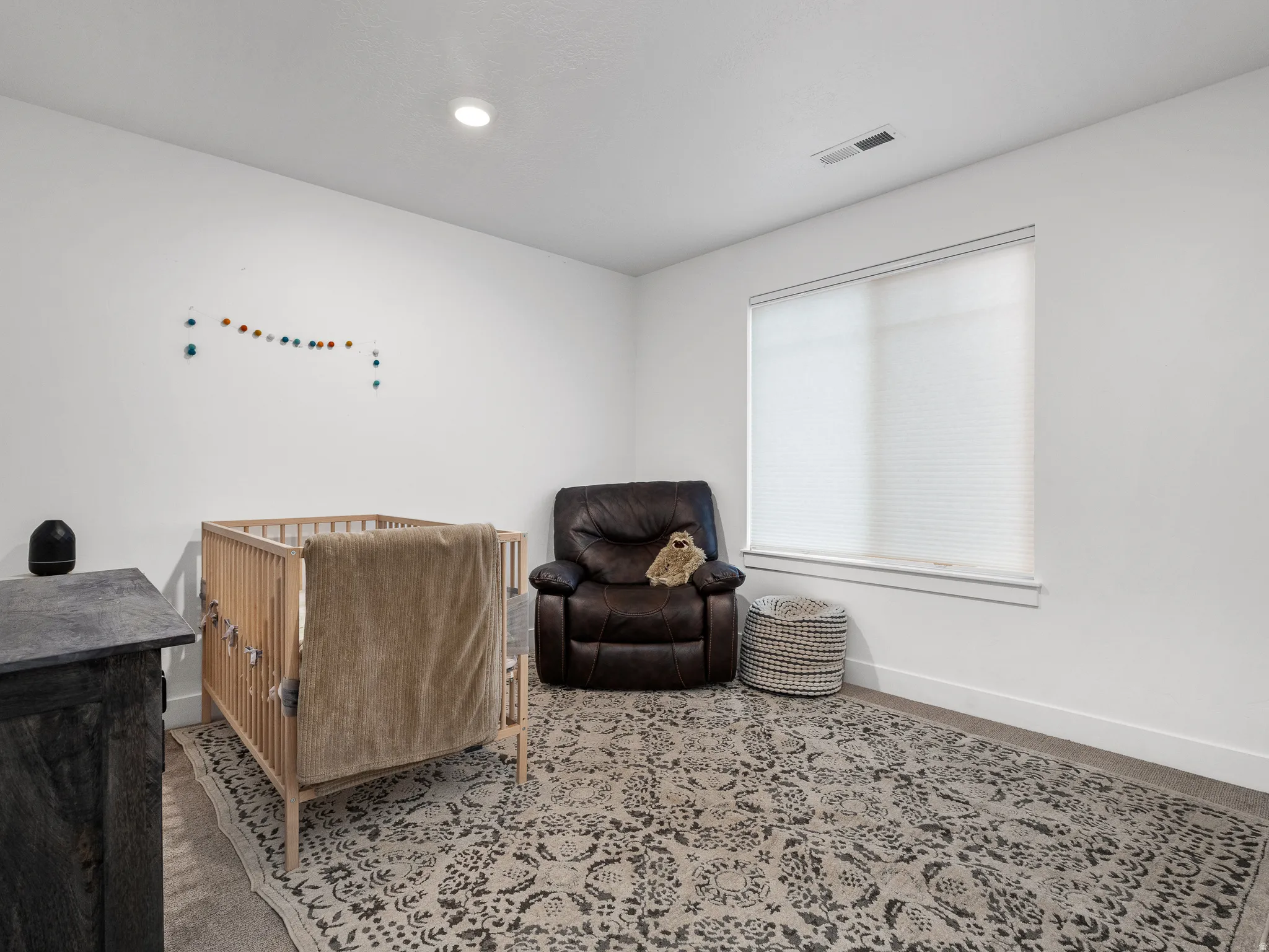Spacious room featuring neutral white walls, recessed ceiling lighting, and a large window with cellular blinds