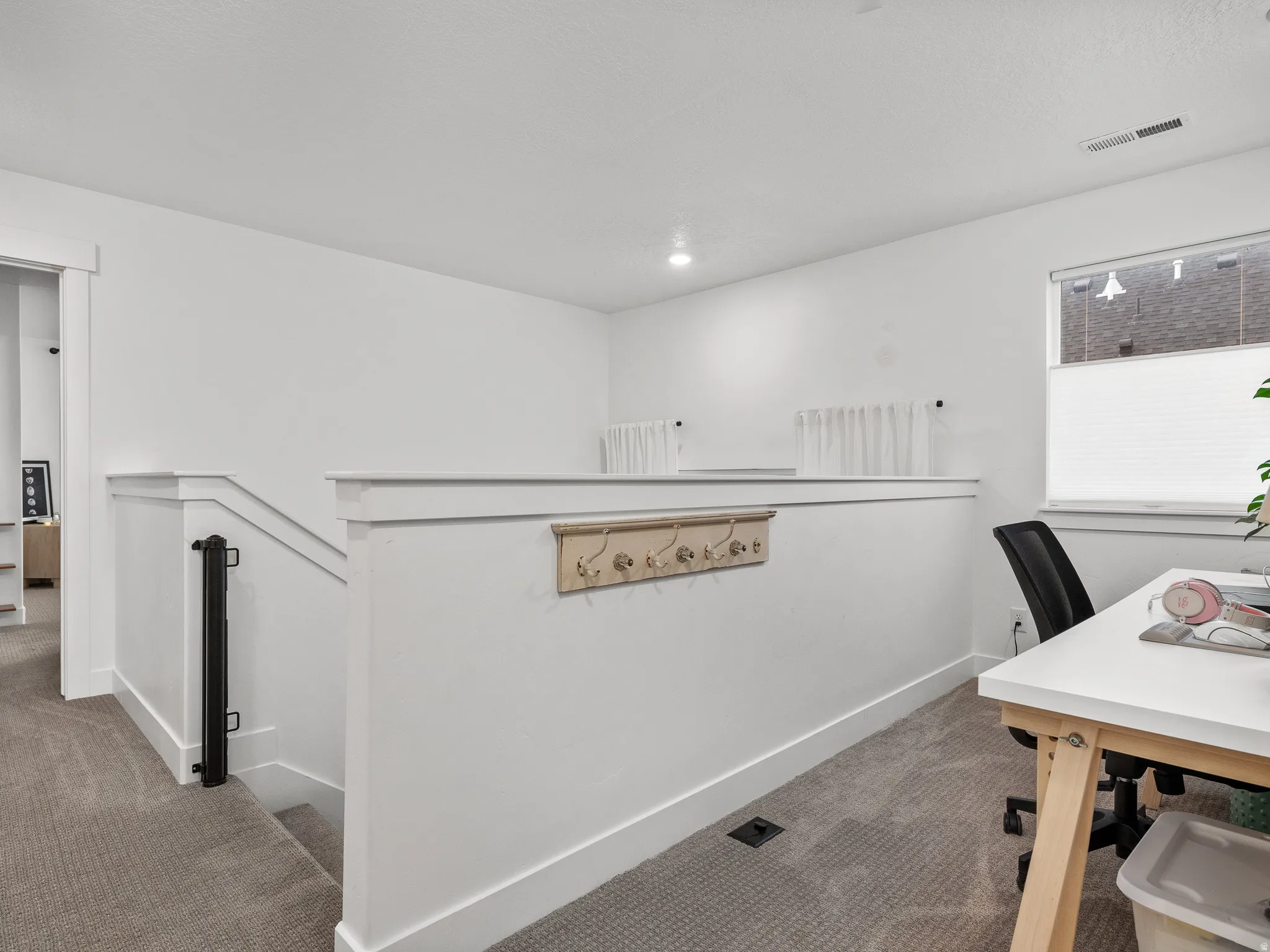 Carpeted landing with white balustrade and baseboards
