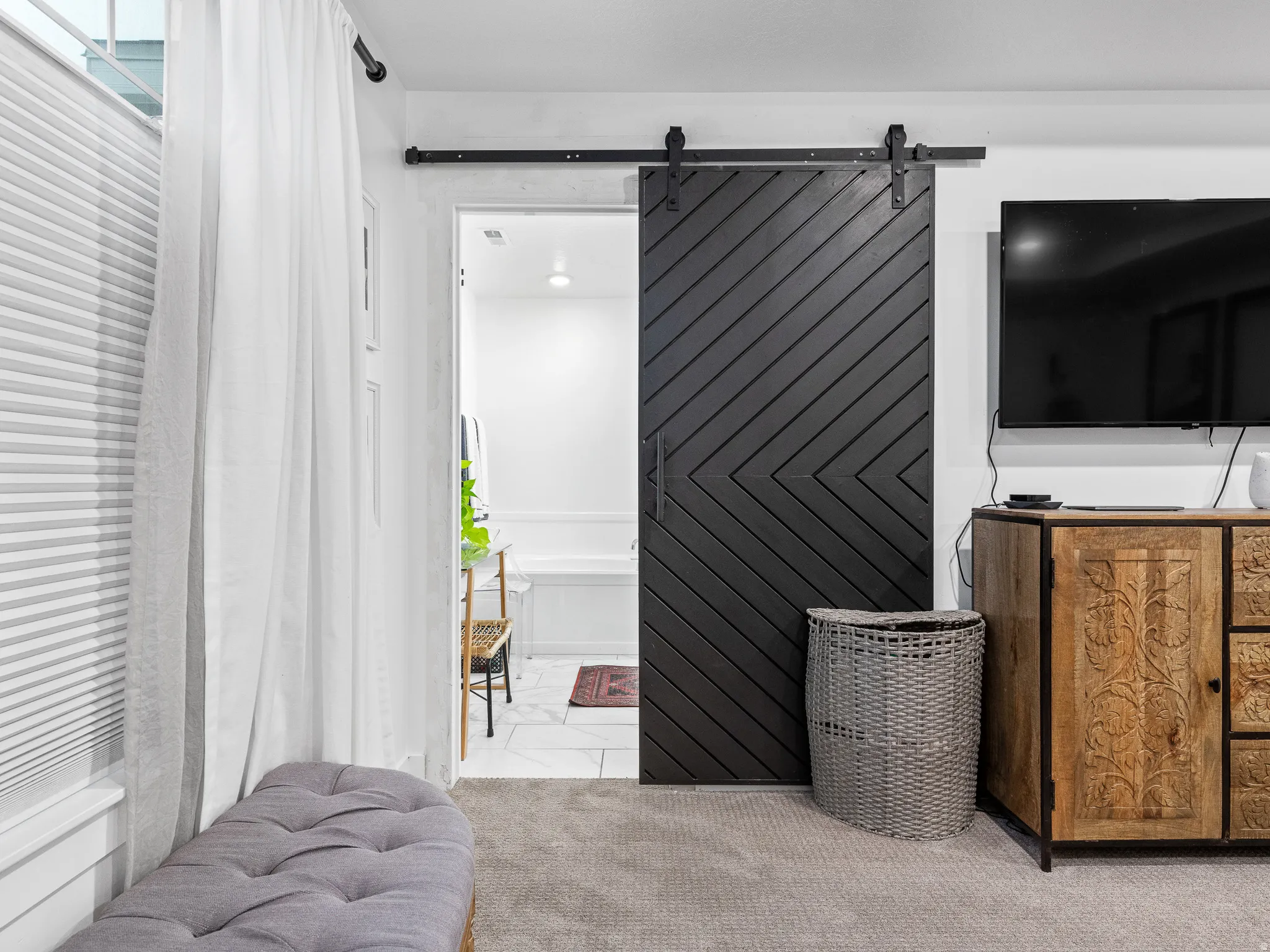 Modern black barn door with chevron paneling, mounted on a black metal track system