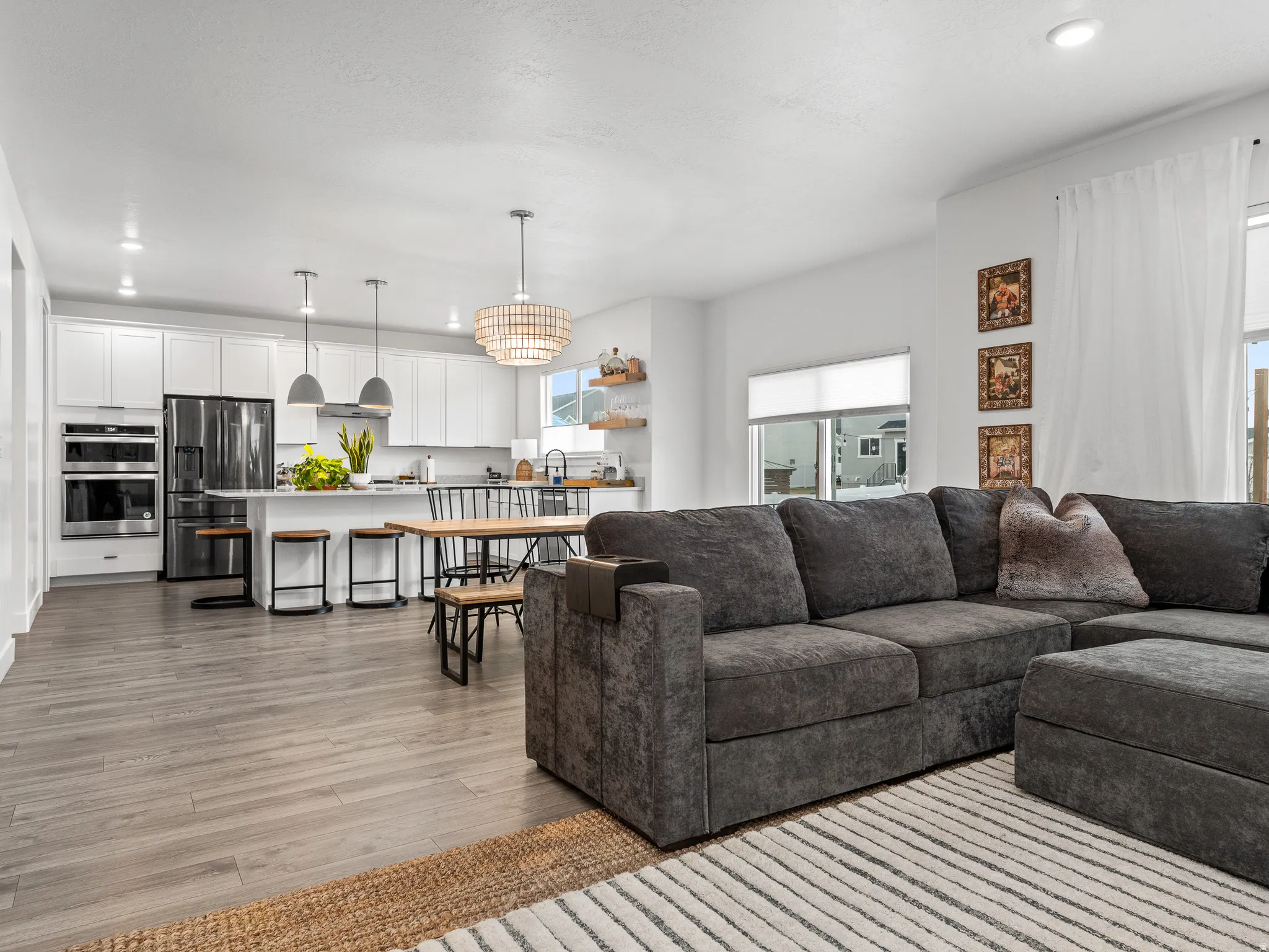Open-concept living space featuring wood-finish flooring, recessed lighting, and a kitchen with white cabinetry