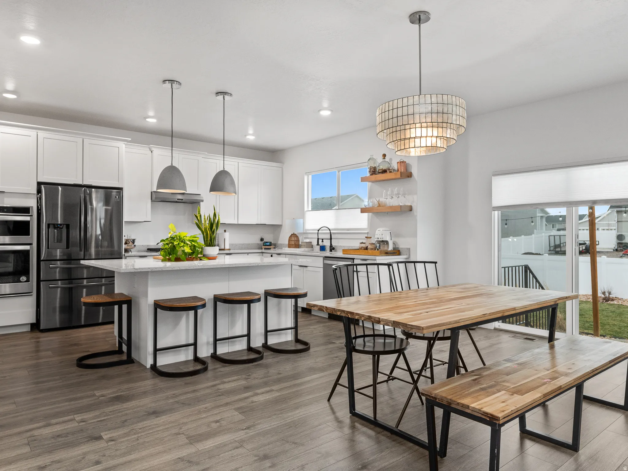 Expansive kitchen featuring a large island with seating, stainless steel appliances, white cabinetry, and wood-finish flooring