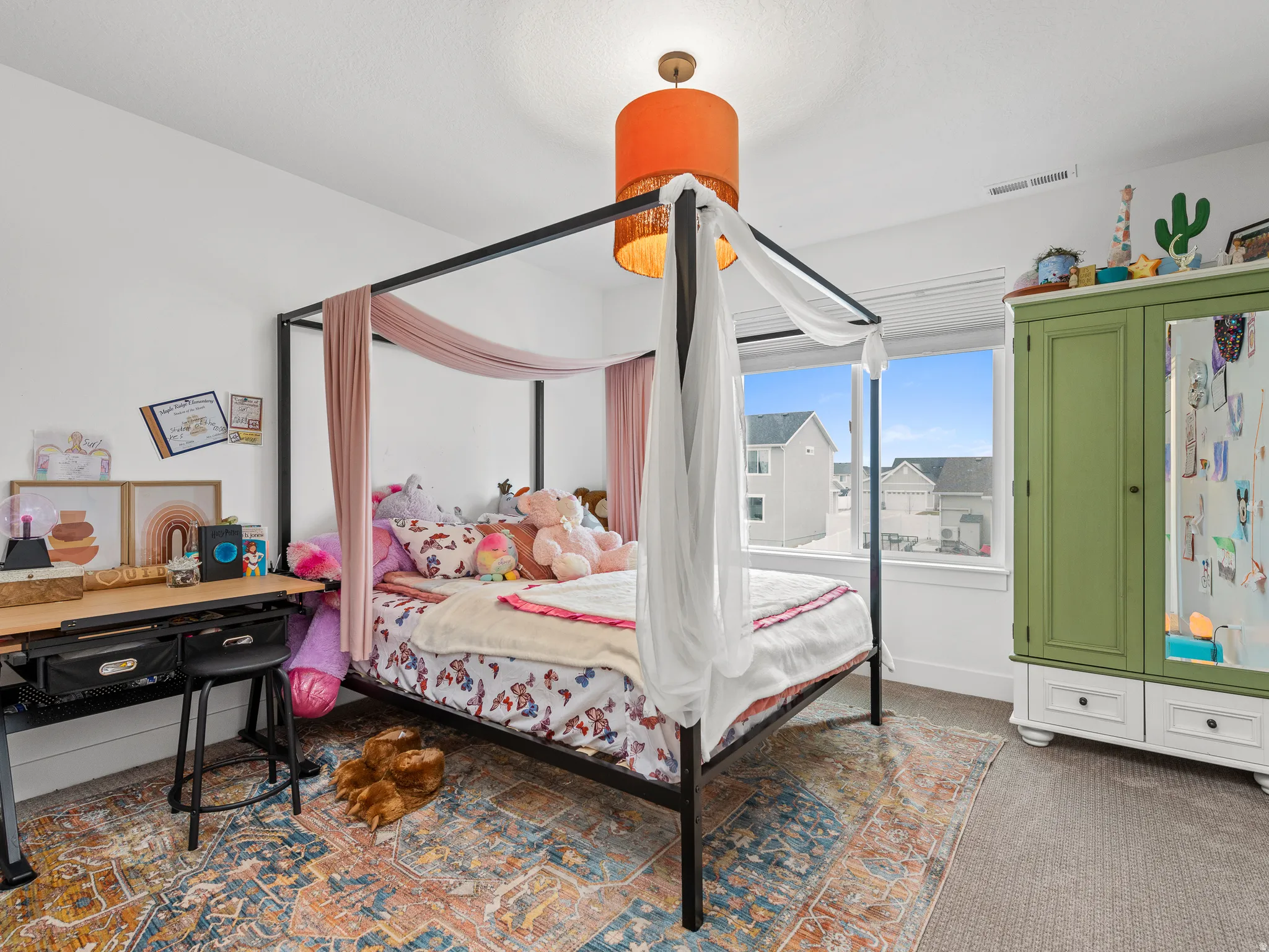 Carpeted bedroom featuring a large window, a built-in wall cabinet, a built-in desk, and a ceiling light fixture