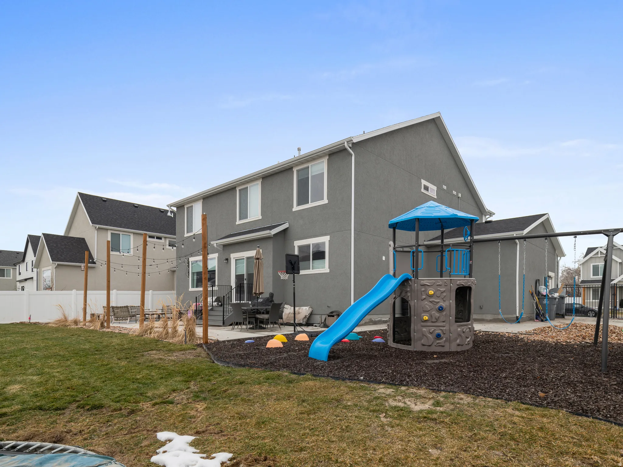 Expansive backyard featuring a concrete patio, a privacy fence, and a two-story gray exterior