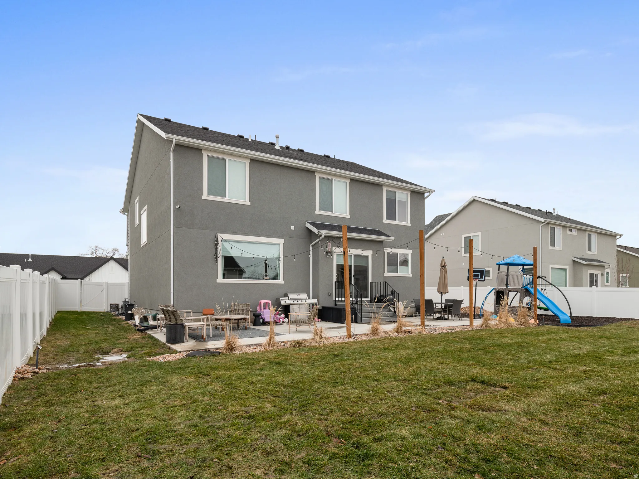 Expansive backyard featuring a manicured lawn, full privacy fencing, and a concrete patio