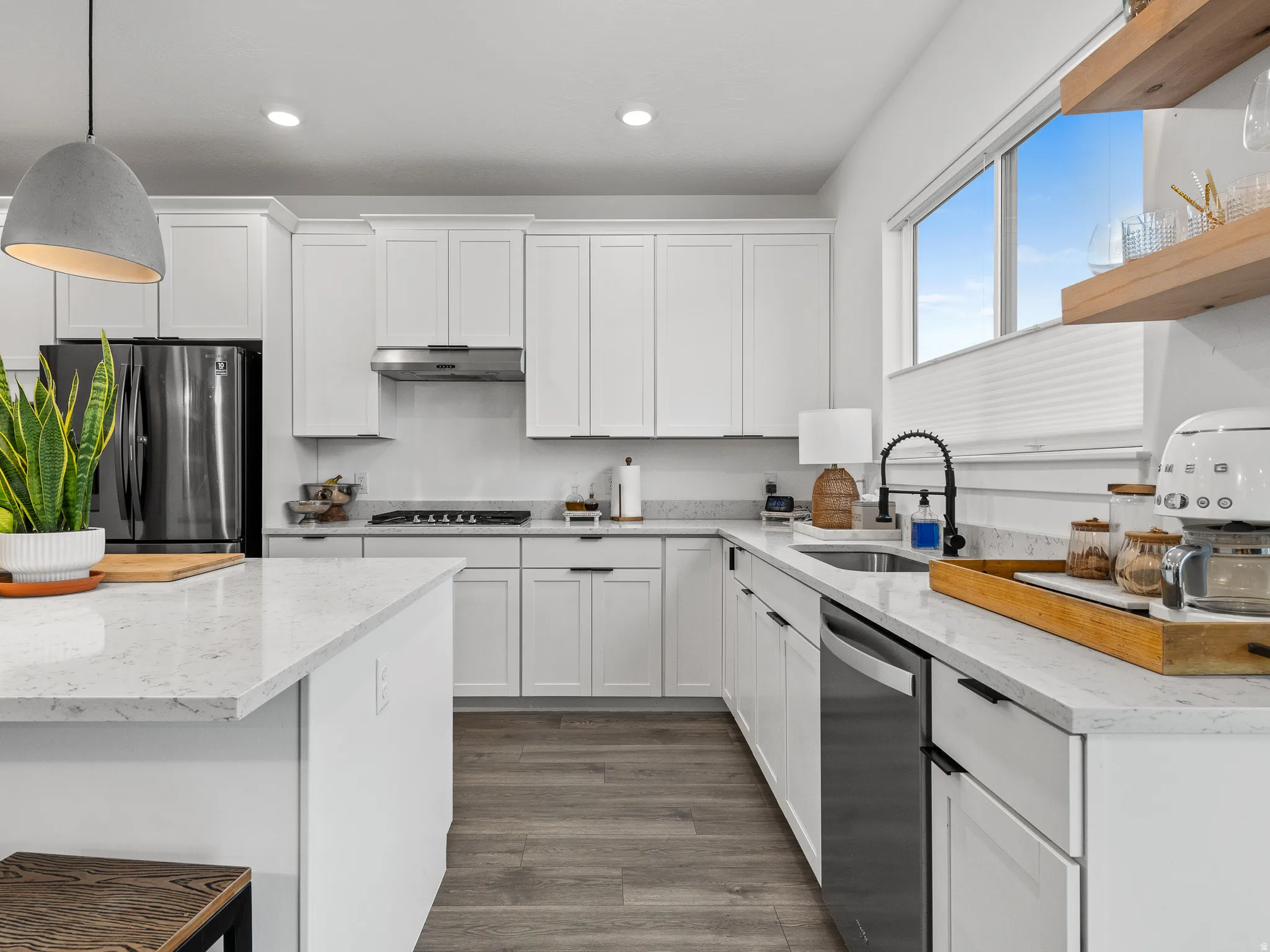 Bright kitchen featuring white cabinetry, light-toned countertops, and wood-finish flooring