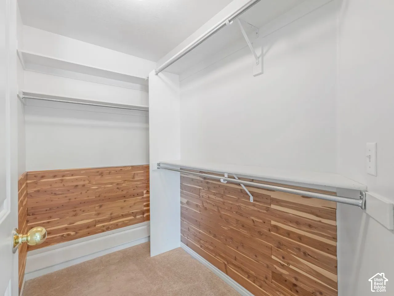 Walk-in closet featuring cedar plank wall accents, multiple clothing rods, integrated shelving, and neutral carpeting